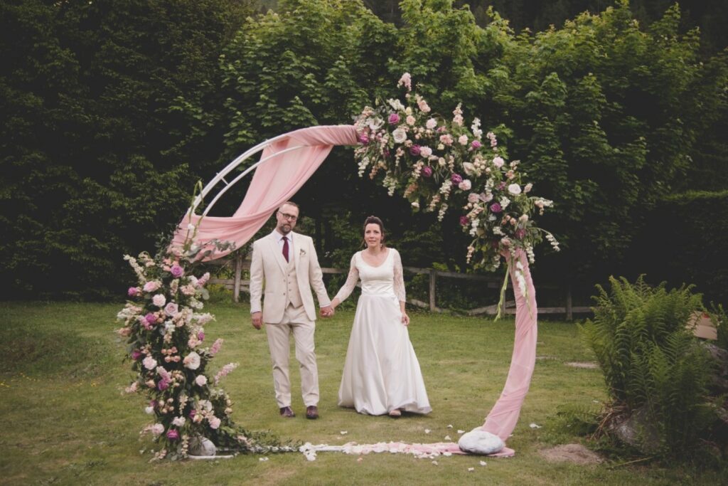 couple de mariés passant sous une arche de fleurs ronde à Chamonix