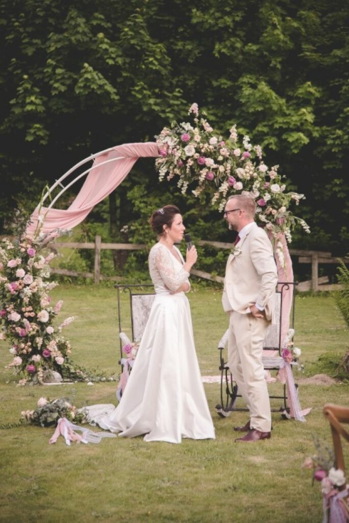 couple en train de s'échanger leur voeux lors d'un mariage à Chamonix devant une belle arche ronde fleurie